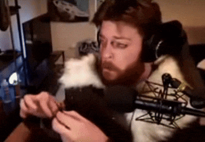 a man with headphones is holding a cat in front of a microphone .