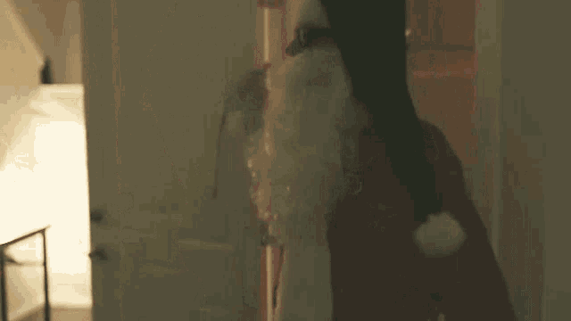 a man dressed as santa claus is standing in a hallway .