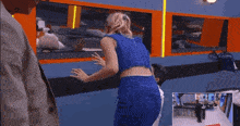 a woman in a blue top is dancing with a man in a white shirt in a room .