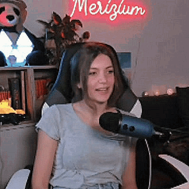 a woman is sitting in a gaming chair in front of a microphone .
