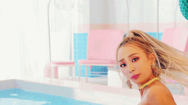 a woman wearing a choker and earrings is sitting in front of a pool
