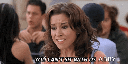 a woman is sitting in a crowd of people and says `` you can 't sit with us abby ''
