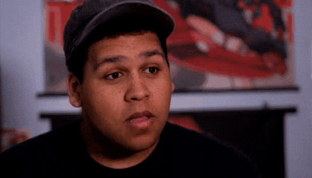 a man wearing a hat and a black shirt is looking at something