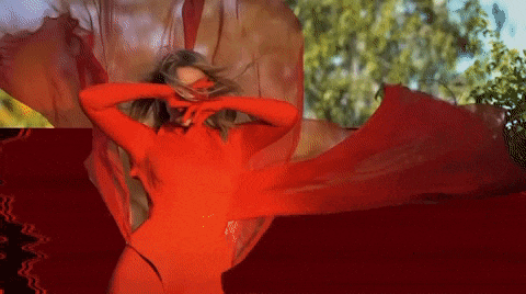 a woman in a red dress is dancing with a red cloth behind her
