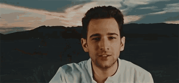 a man in a white shirt is standing in front of a desert landscape .