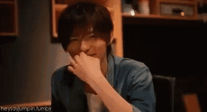 a man is sitting at a table with his hand on his mouth .