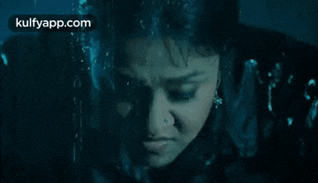 a close up of a woman 's face in the water with water drops on her face .