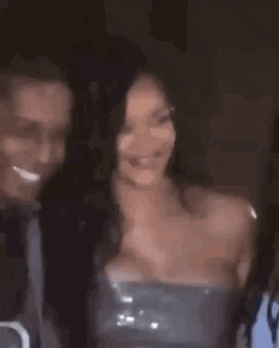 a man and a woman are standing next to each other and smiling . the woman is wearing a strapless dress .