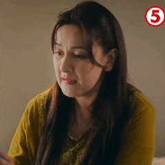 a woman in a yellow shirt is looking at her phone with the number 5 in the corner