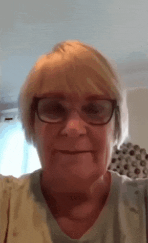 a close up of a woman wearing glasses and a sweater