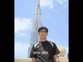 a man stands in front of a very tall building with a black shirt that says ' pritip poetel ' on it