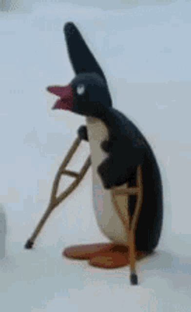 a penguin with crutches is sitting on the snow .