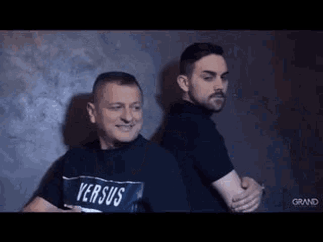 two men are standing next to each other and hugging each other .