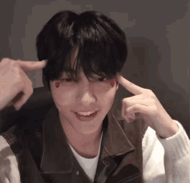a young man with hearts on his face is making a funny face with his fingers .