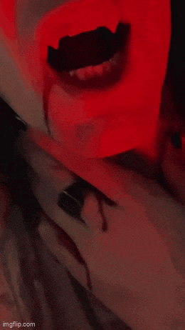 a close up of a person 's mouth with blood coming out of it in a red light .