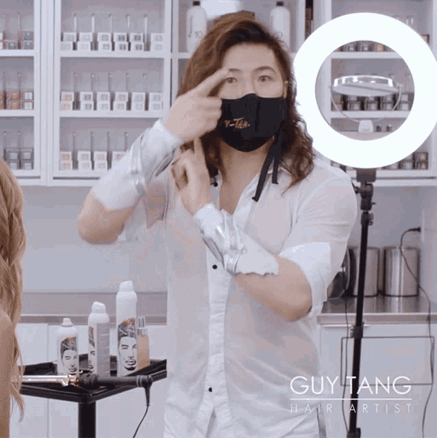 a guy tang hair artist wearing a mask adjusts his hair
