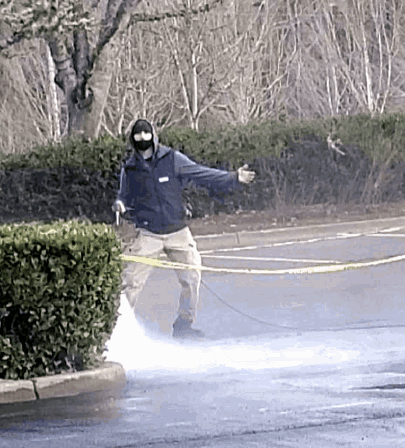 a man wearing a mask is spraying a parking lot