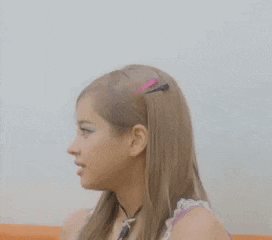 a young girl is making a surprised face while sitting in an orange chair .