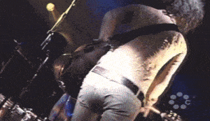 a man with a tattoo on his back is playing guitar