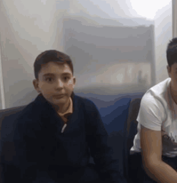 a boy and a girl are sitting next to each other on a couch and looking at something .