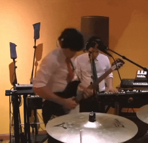 a man playing a guitar in front of a drum set