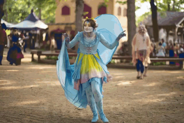 a woman in a blue and yellow fairy costume is dancing