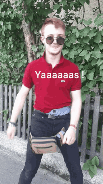a man wearing sunglasses and a red shirt that says yaaaas