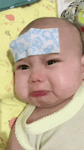 a baby with a thermometer on his forehead crying
