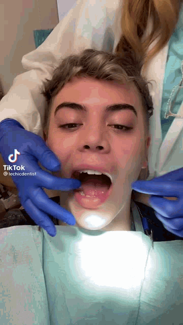 a young man is getting his teeth examined by a dentist