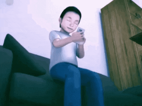 a boy is sitting on a couch looking at a cell phone .