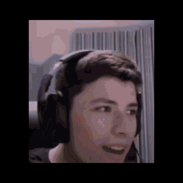a close up of a man wearing headphones and making a funny face .