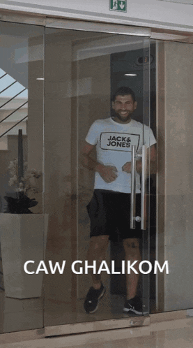 a man wearing a jack & jones t-shirt is standing in a glass doorway