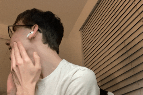 a man wearing a pair of white ear buds is covering his face