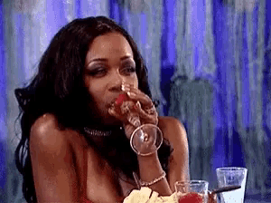 a woman is sitting at a table eating chips and drinking a glass of wine .