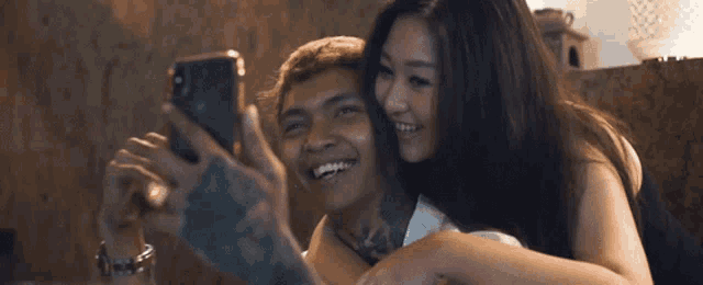 a man and woman are taking a selfie with a cell phone