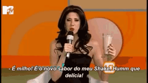 a woman is holding a milkshake and talking into a microphone .