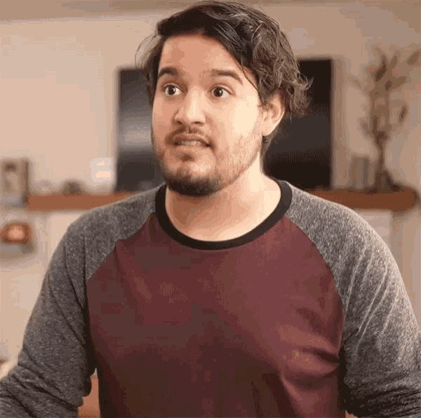 a man with a beard wears a maroon and grey shirt