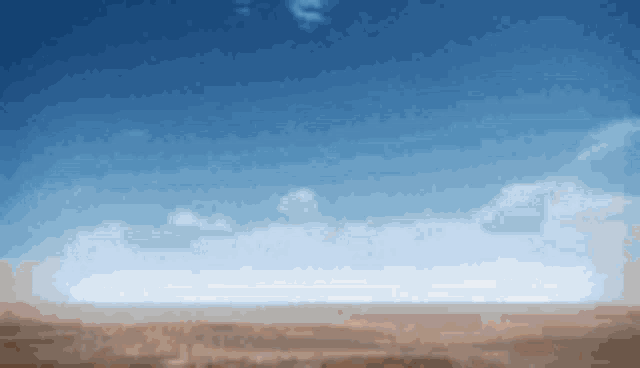 a blurred image of a desert with a blue sky in the background