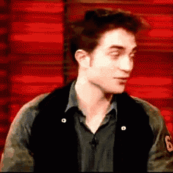 a man wearing a black vest and a black shirt is standing in front of a red background