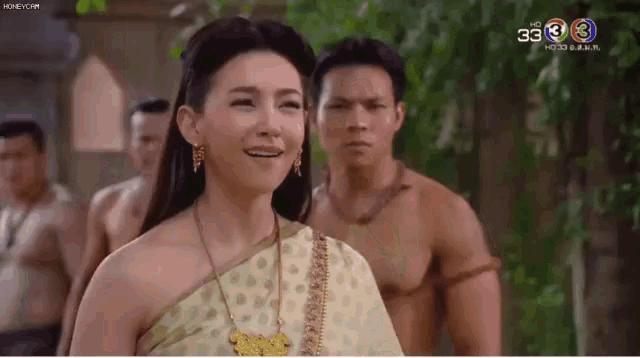 a woman is smiling in front of a group of men without shirts .