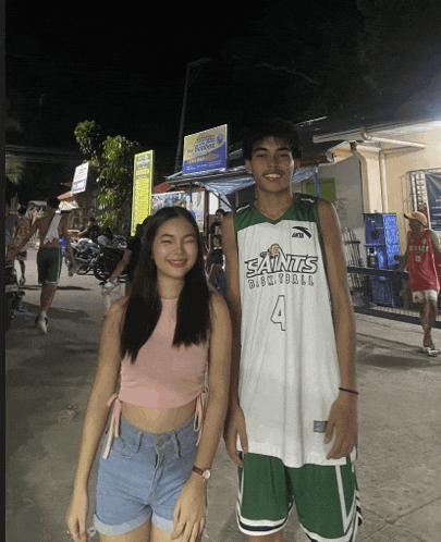 a man wearing a saints basketball jersey poses with a woman