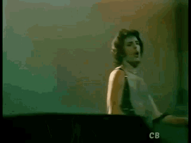 a man without a shirt is singing into a microphone while playing a guitar on a stage .