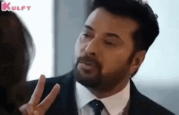 a man in a suit and tie is making a peace sign .