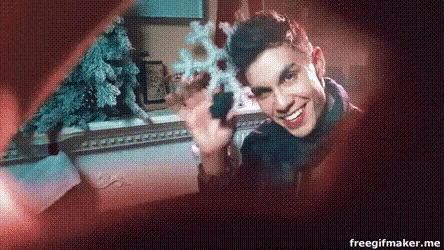 a man is smiling while holding a snowflake in front of a christmas tree