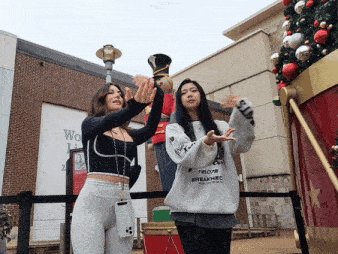 two women standing in front of a christmas tree one wearing a sweatshirt that says t22078 breakneck