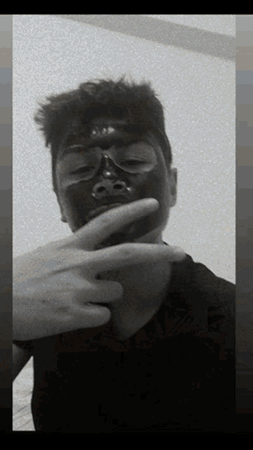 a man with a black mask on his face is making a peace sign