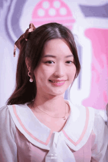 a girl with a bow in her hair is wearing a pink dress
