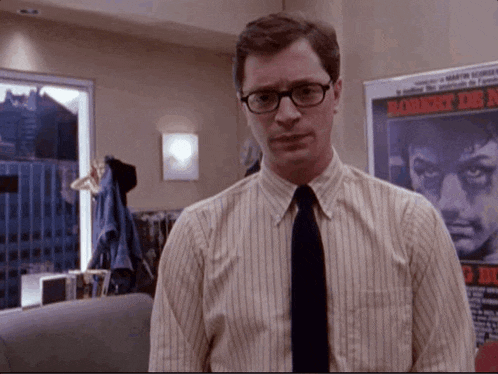 a man in a striped shirt and tie is standing in front of a poster that says roberto de n