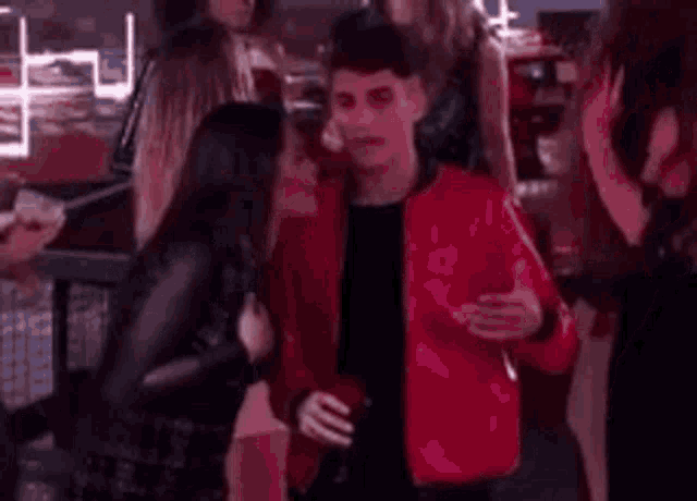 a man in a red jacket is standing next to a woman in a black dress at a party .