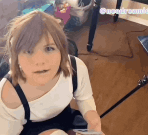 a girl with a white shirt and black suspenders looks at the camera with a watermark that says needdreamie